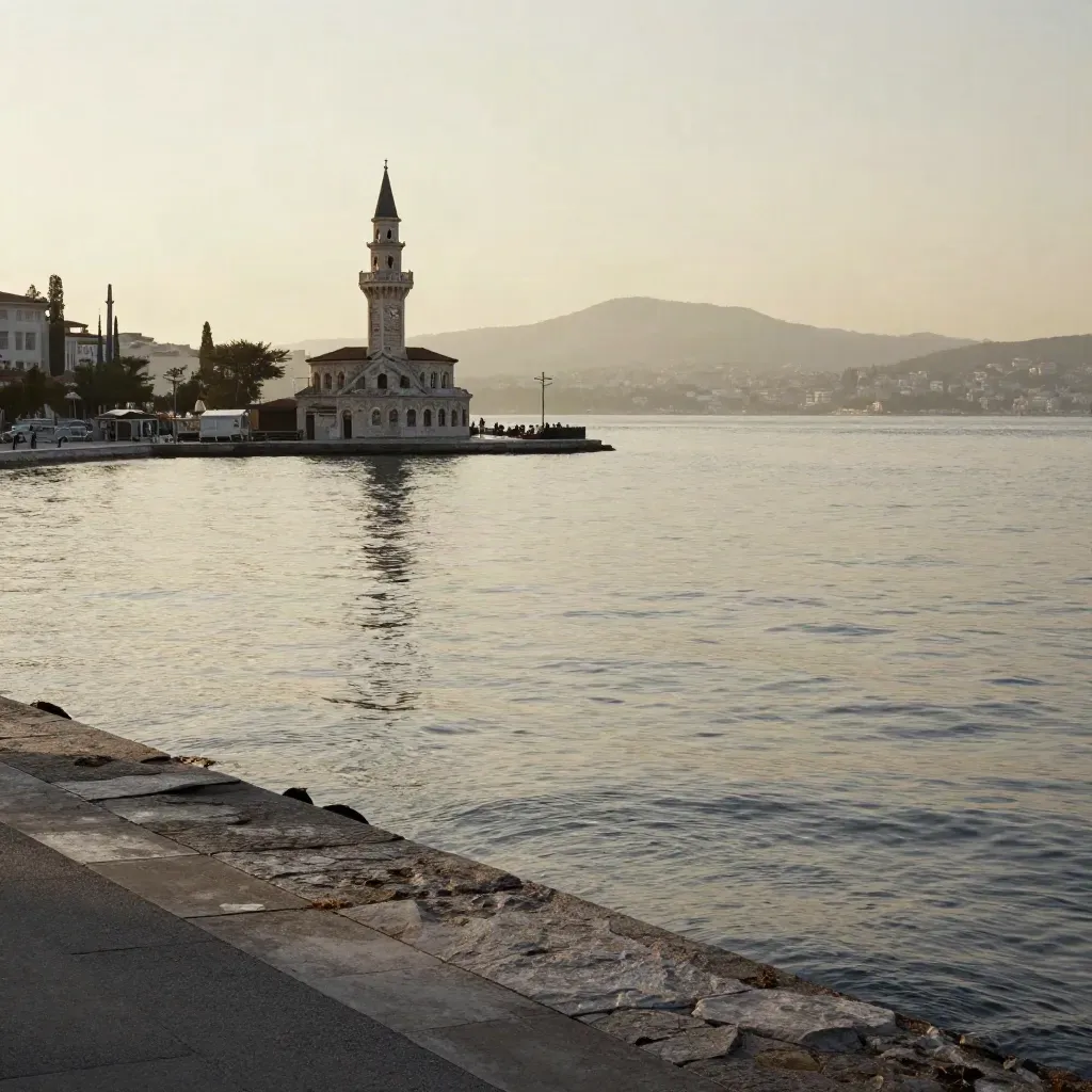 İzmir Körfezi üzerinde sisli Konak Saat Kulesi, alçak gün ışığında sakin kıyı manzarası.